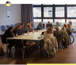Group of people meeting and discussing around a table, some people are in wheelchairs